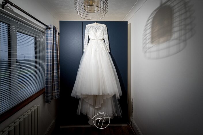 wedding dress hanging in blue background