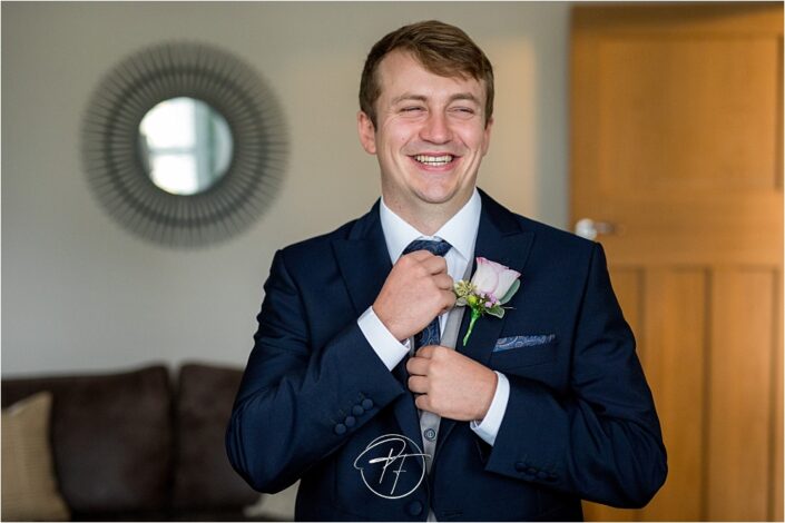 Groom in natural light straightening his tie